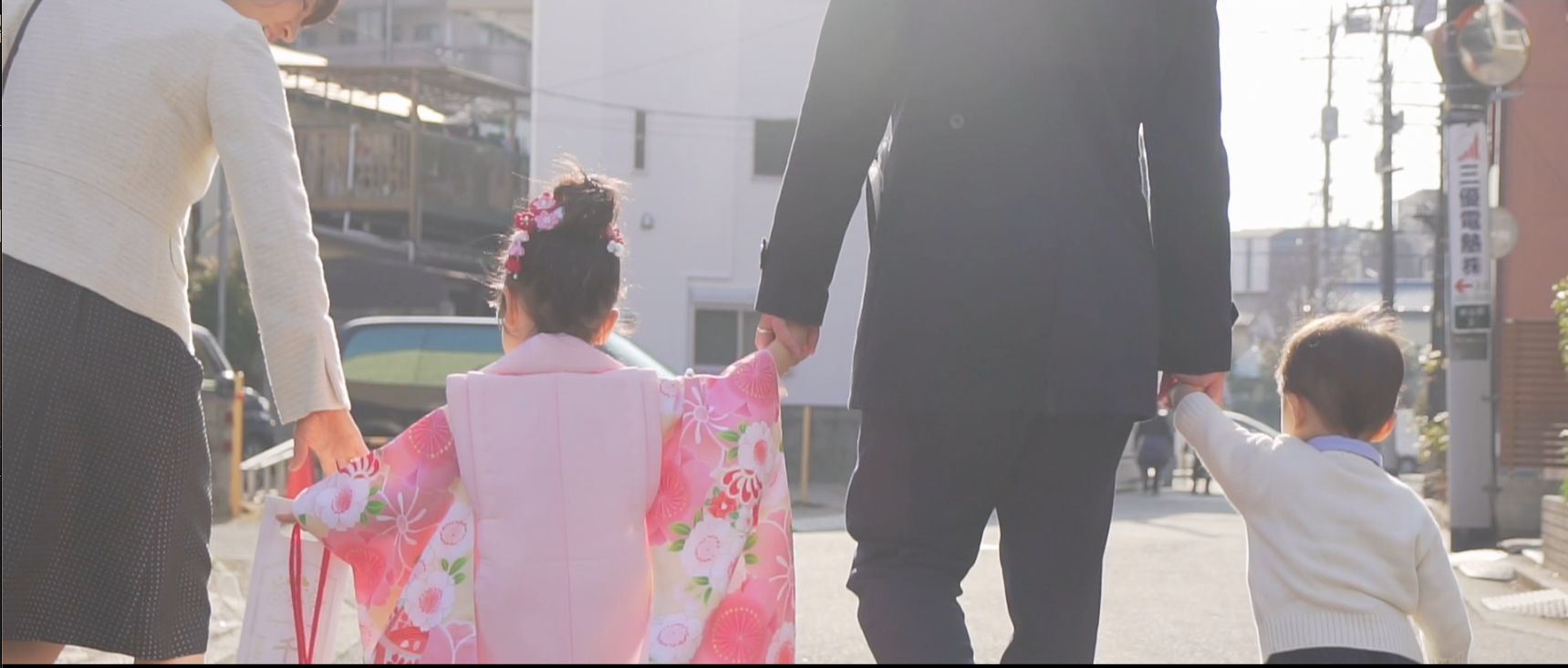 七五三の日、家族に手を引かれて歩く子どもの後ろ姿