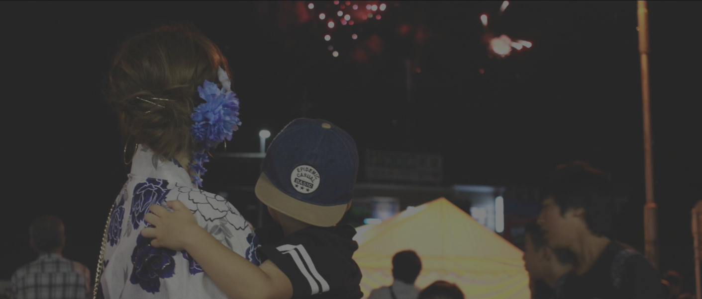 夜の祭りで子どもを抱く家族